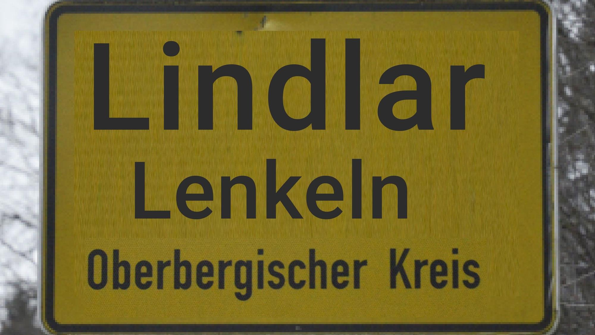 Die Bildmontage zeigt das Lindlarer Ortseingangsschild mit Zusatz des Namens in Mundart (Lenkeln).