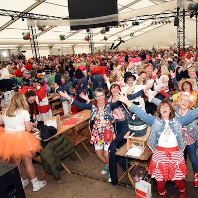 Ein volles Festzelt. Zahlreiche verkleidete Damen feiern Karneval.