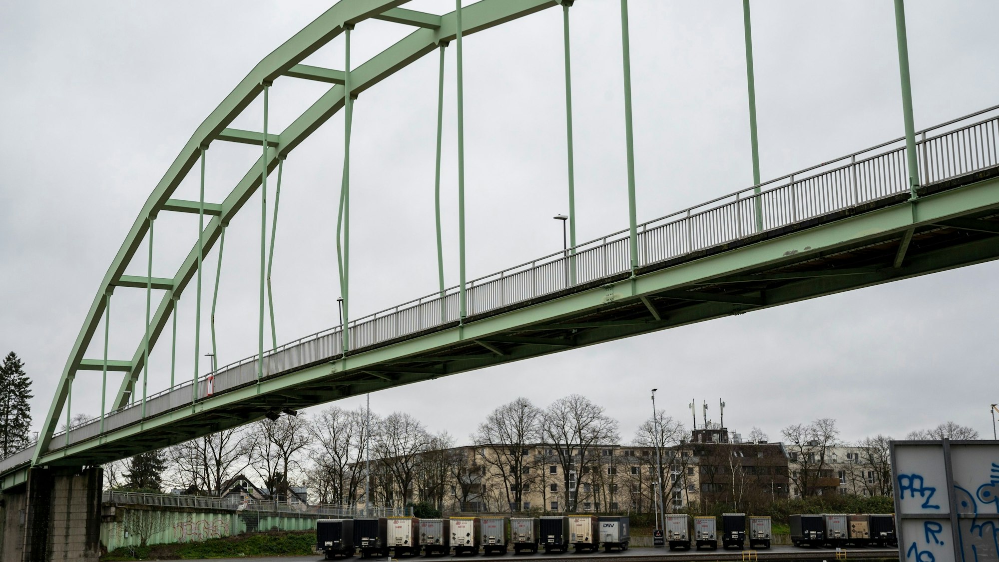 Blick von unten auf eine Brücke, im Hintergrund sind Häuser zu sehen.