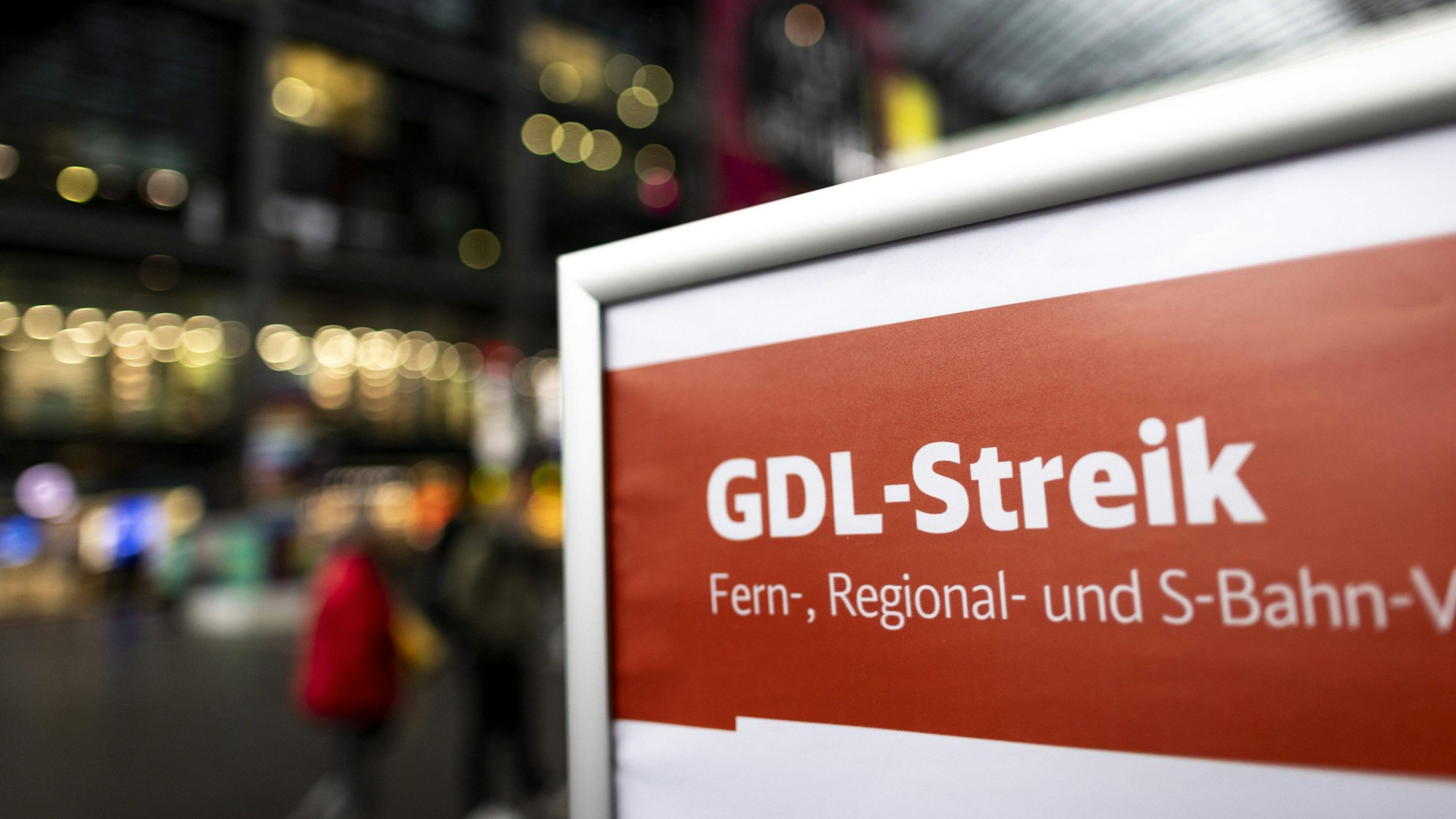 Auf einem Schild am Berliner Hauptbahnhof ist in weißer Schrift auf rotem Grund zu lesen: „GDL-Streik – Fern-, Regional- und S-Bahn-Verkehr“. Im Hintergrund sind verschwommen Reisende und die Fassaden von Ladenlokalen im Bahnhof zu erkennen.
