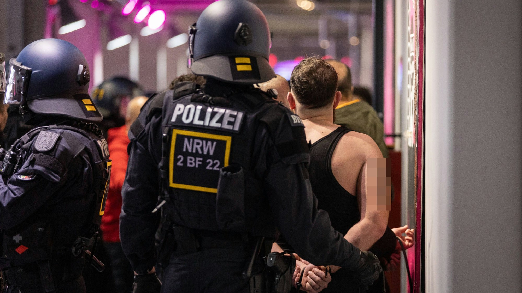 Die Polizei führt einen Fan mit Handschellen ab.