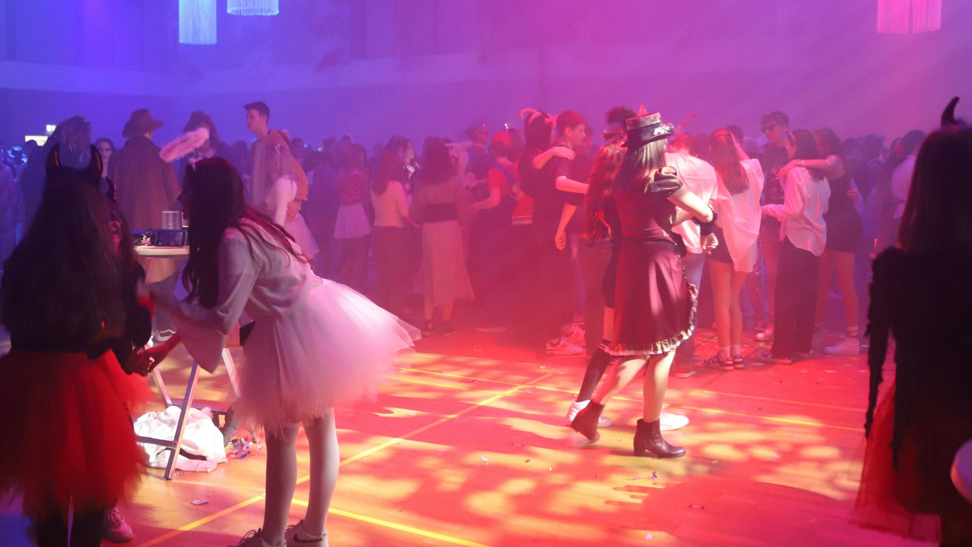 Kostümierte Jugendliche auf der Tanzfläche in einer Mehrzweckhalle.