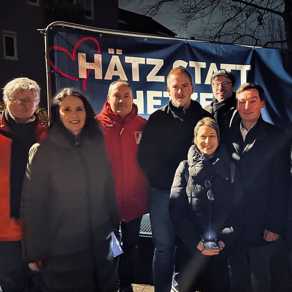 Männer und Frauen stehen vor einem Banner mit der Aufschrift „Hätz statt Hetze“.