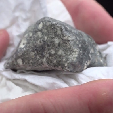 Ein mutmaßliches Meteoritenteil liegt in einem Papiertaschentuch.