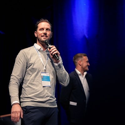 Christoph Schindler, Geschäftsführer VfL Gummersbach, spricht auf der Bühne in ein Mikrofon.