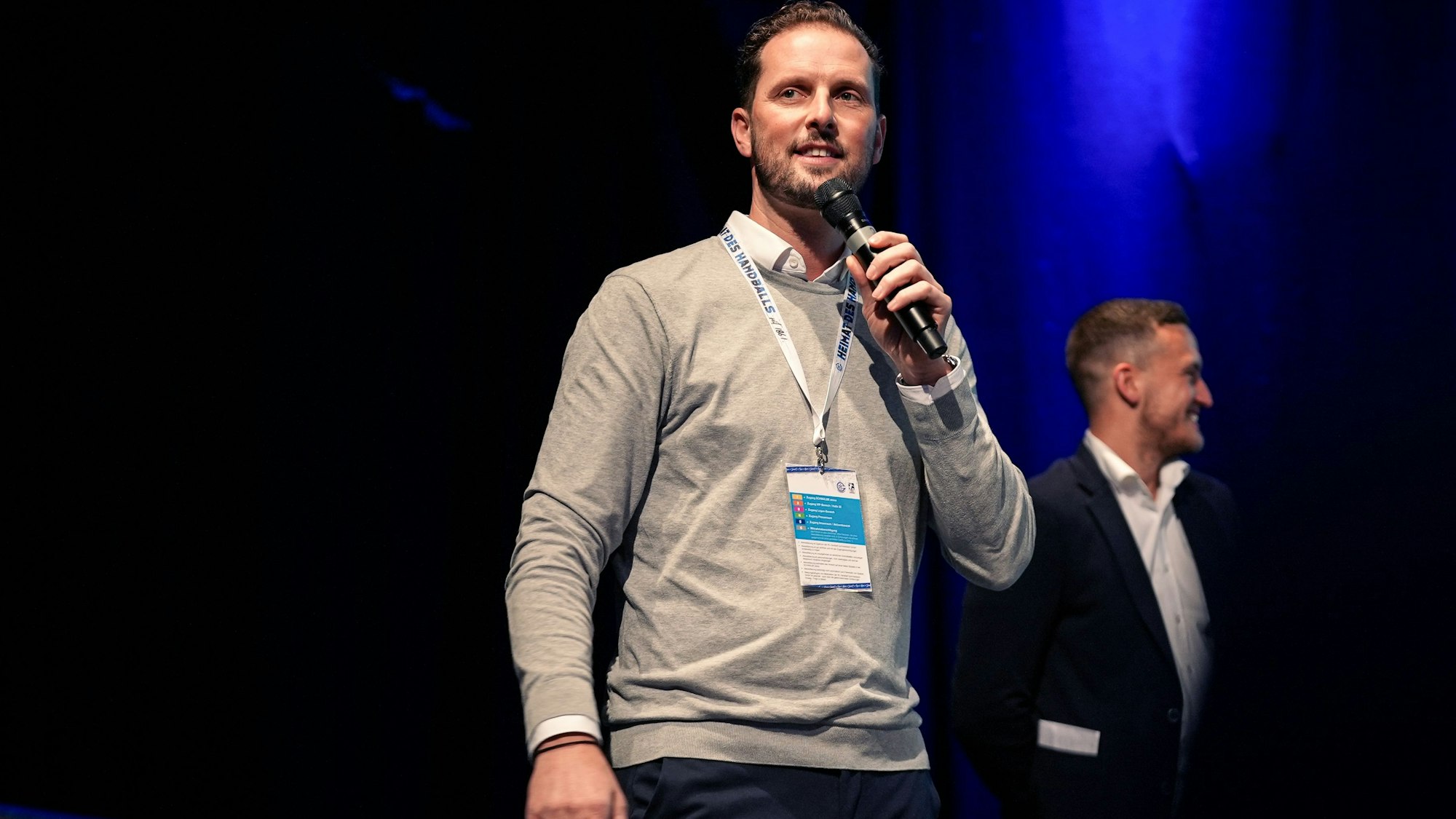 Christoph Schindler,  Geschäftsführer VfL Gummersbach, mit Mikrophon auf der Bühne.