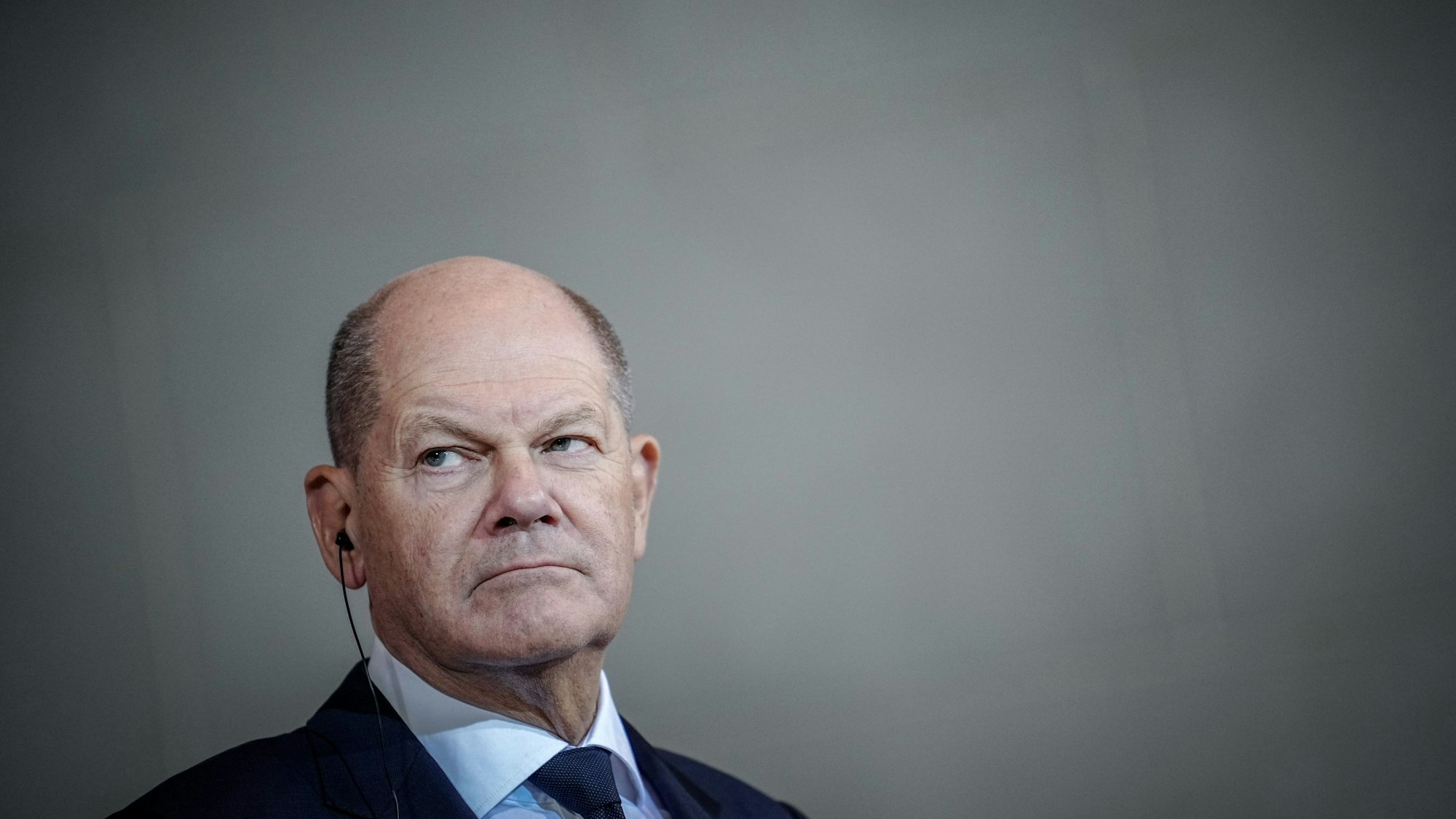 Bundeskanzler Olaf Scholz (SPD) schau auf etwas außerhalb des Bildbereichs während seine Mundwinkel nach unten zeigen.