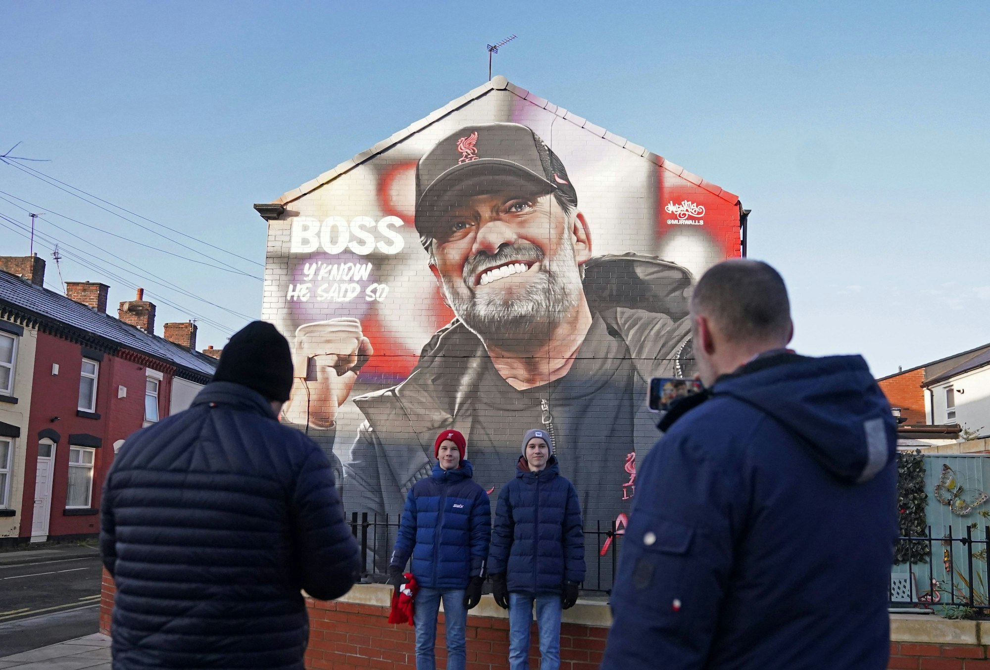 Liverpool-Fans posieren vor einer Hauswand mit einem Porträt von Jürgen Klopp