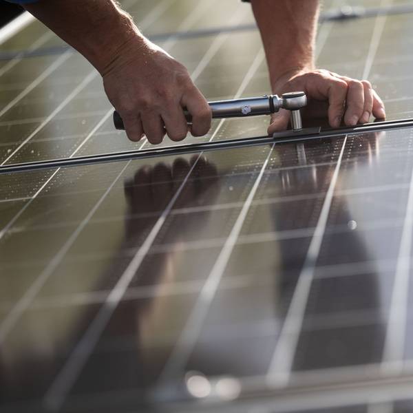 Ein Arbeiter montiert Photovoltaikmodule auf einem Dach.