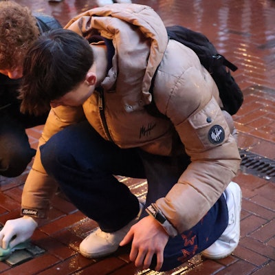 Zwei Schüler reinigen Stolpersteine in der Opladener Fußgängerzone.