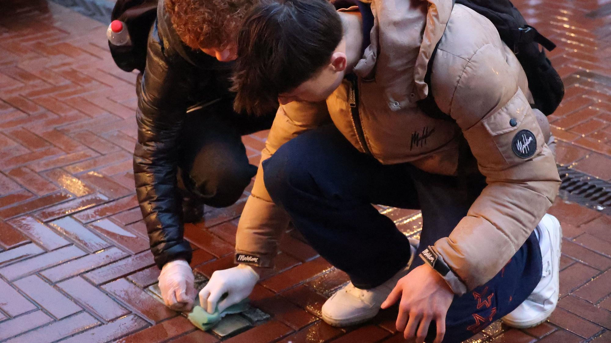 Zwei Schüler reinigen Stolpersteine in der Opladener Fußgängerzone.