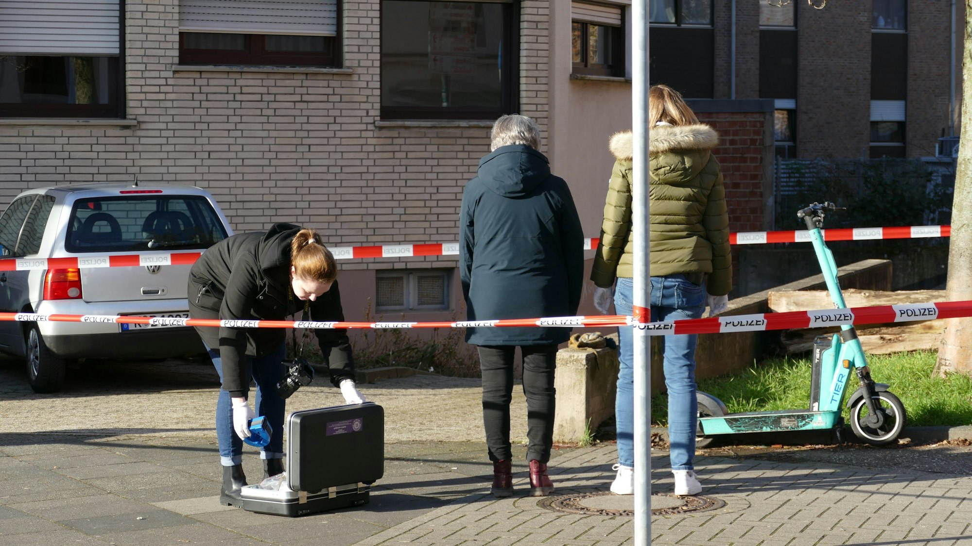 Drei Frauen stehen in einem durch Flatterband abgesperrten Bereich.