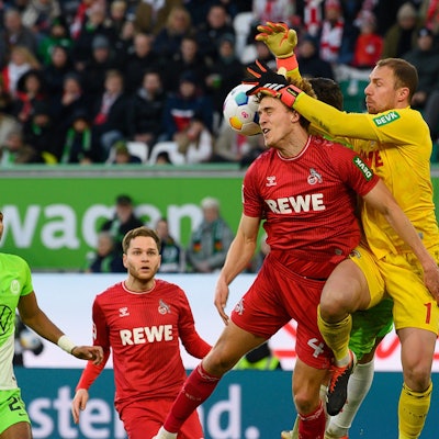 Kölns Torwart Marvin Schwäbe (r) und Kölns Timo Hübers kämpfen mit Wolfsburgs Jonas Wind (verdeckt) um den Ball.