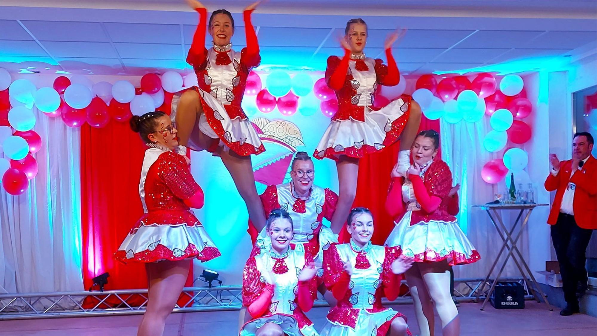 Sieben junge Frauen der Tanzgarde zeigen eine Akrobatische Pose auf einer Bühne.