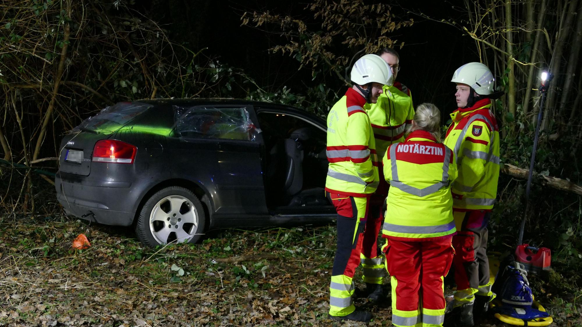 Rettungskräfte stehen um das verunglückte Auto herum.