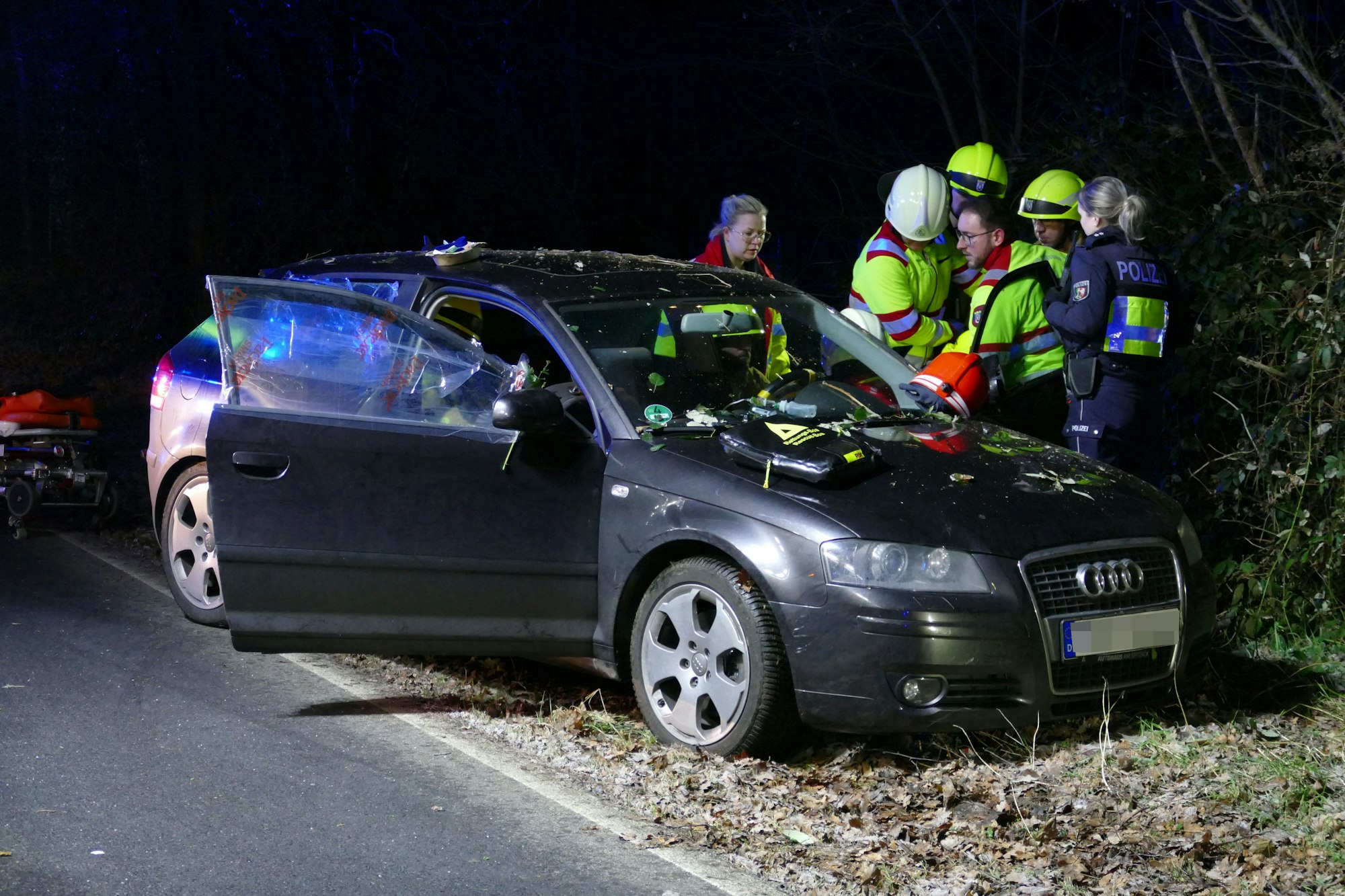 Rettungskräfte stehen um das Auto herum.