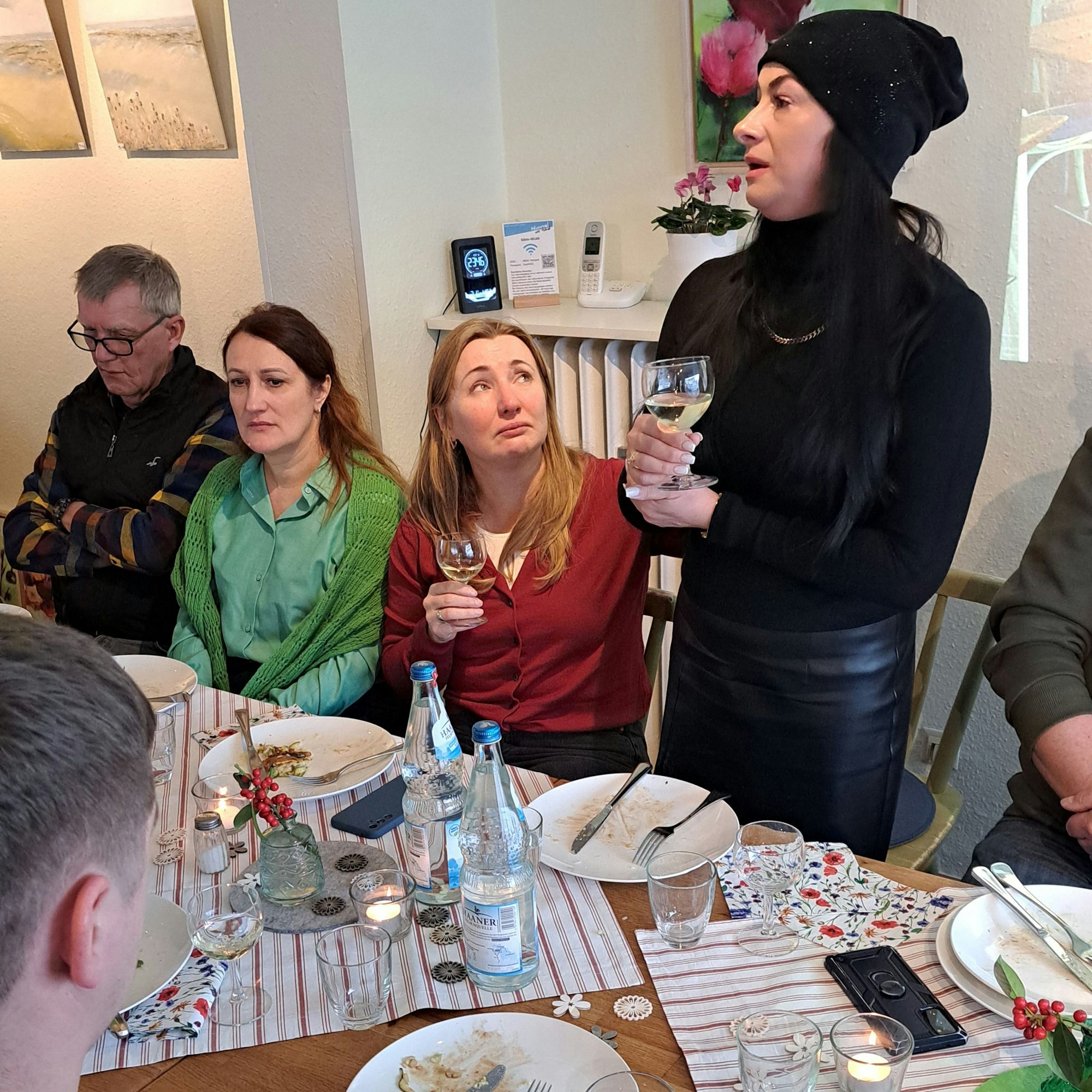 Eine Vertreterin der Delegation aus Butscha hält eine Rede, die anderen schauen ergriffen.