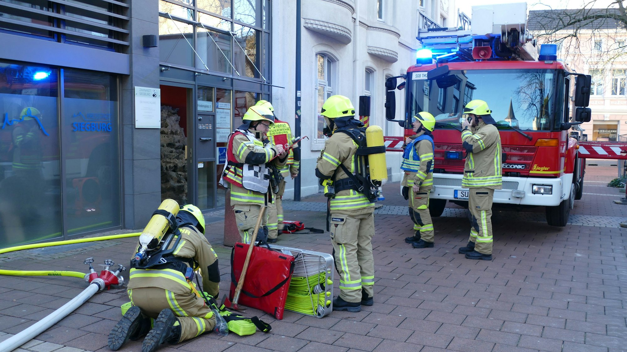 Feuerwehrleute vor dem Eingang des Gebäudes am Friedensplatz.