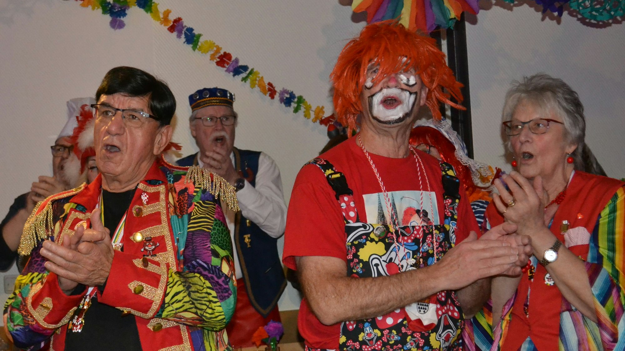 Bunt kostümierte Männer und Frauen klatschen und singen.