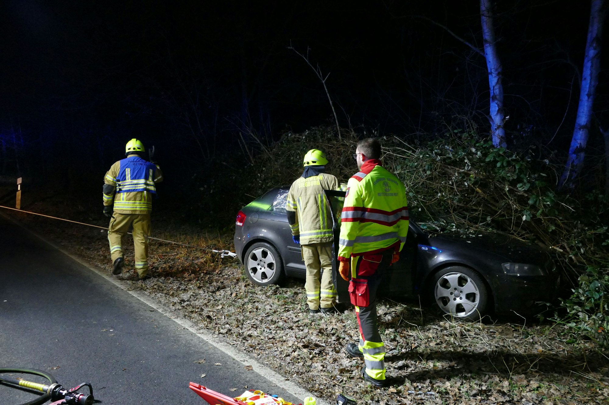 Feuerwehrleute ziehen ein Auto mit einer Seilwinde weg.
