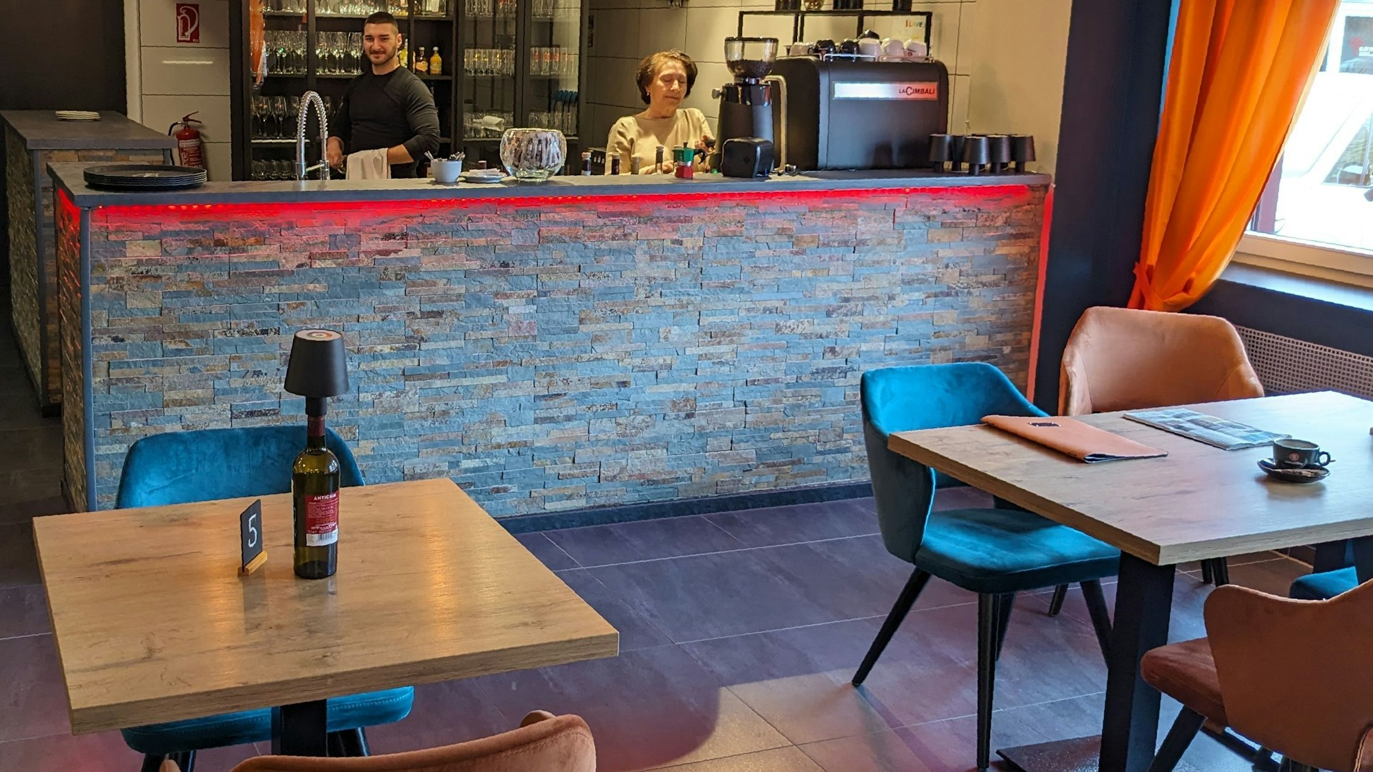 Blick in den Gastraum des Bistro Lenti in Kommern. Riccardo Proietto und Stella Lenti stehen hinter der Theke.