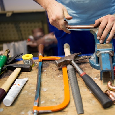 Ein Mann arbeitet an einem Schraubstock. Experten in Nordrhein-Westfalen rechnen unter anderem wegen des demografischen Wandels mit Schwierigkeiten bei der Unternehmensnachfolge in Handwerks- oder Industriebetrieben.