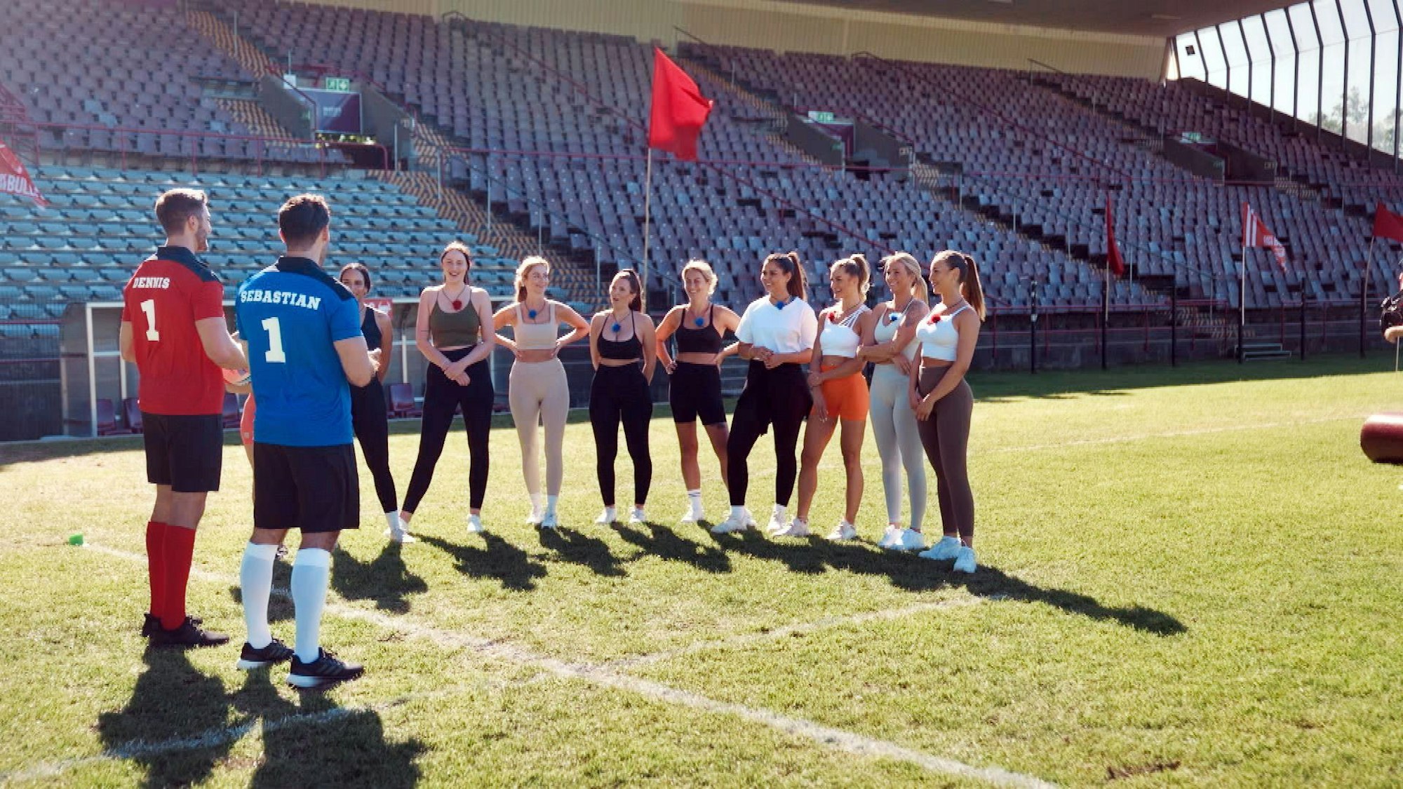 Zwei Männer und zehn Frauen stehen auf einem Rugby-Feld.