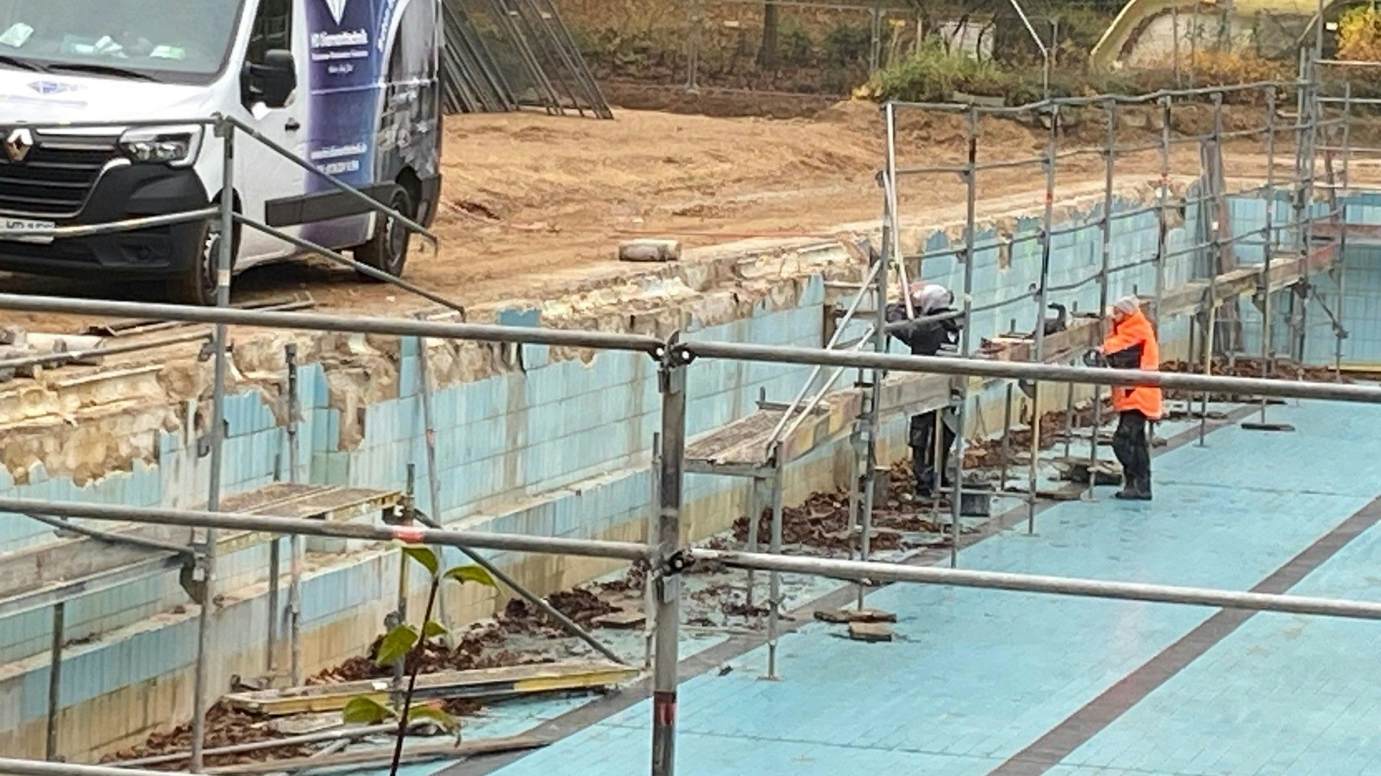 Auf dem Foto steht ein Bauarbeiter im leeren Becken des Terrassenfreibads Frechen.