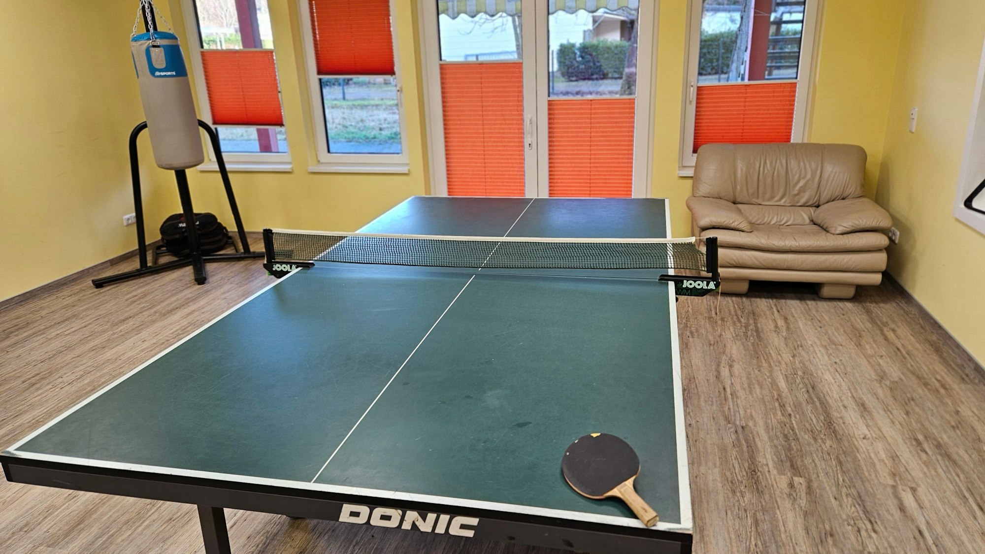 Im Aufenthaltsraum stehen eine Tischtennisplatte, ein Boxsack sowie eine Couch.