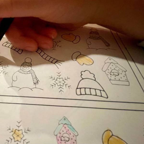 Das Bild zeigt die Hände eines Kindergartenkindes, das im Vorschulheft Bilder ausmalt.