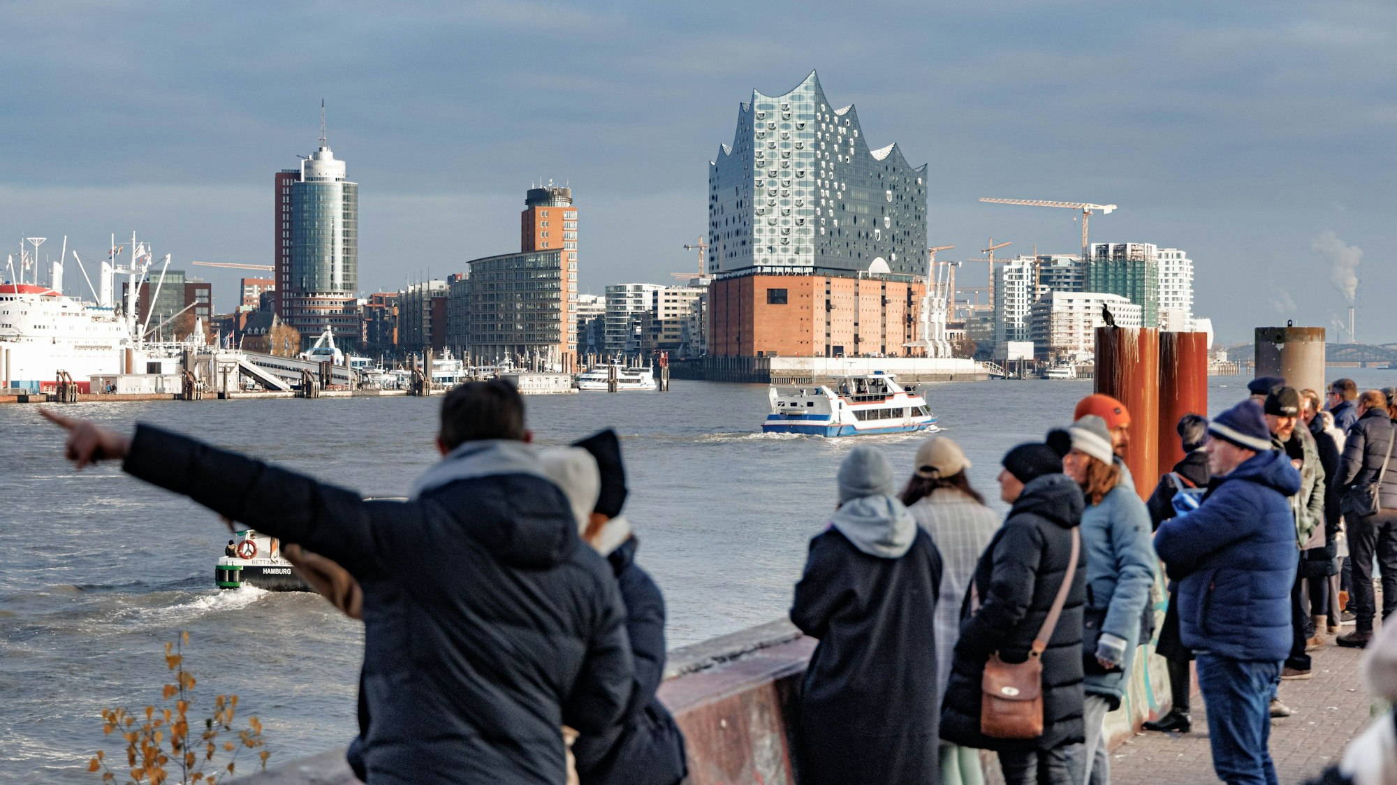 Vom Bornsteinplatz aus betrachten Passanten über die Elbe hinweg das Panorama der Hansestadt – im Hintergrund ist die Elbphilharmonie zu sehen.