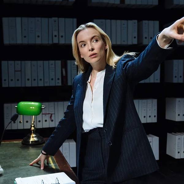 Die englische Schauspielerin Jodie Comer in „Prima facie“, ein Ein-Personen-Stück am Londoner West End und am New Yorker Broadway. Sie steht an einem Schreibtisch vor Aktenregalen, gestikuliert mit ausgestrecktem Arm und Zeigefinger.