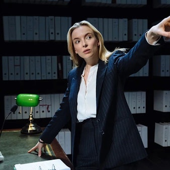 Die englische Schauspielerin Jodie Comer in „Prima facie“, ein Ein-Personen-Stück am Londoner West End und am New Yorker Broadway. Sie steht an einem Schreibtisch vor Aktenregalen, gestikuliert mit ausgestrecktem Arm und Zeigefinger.