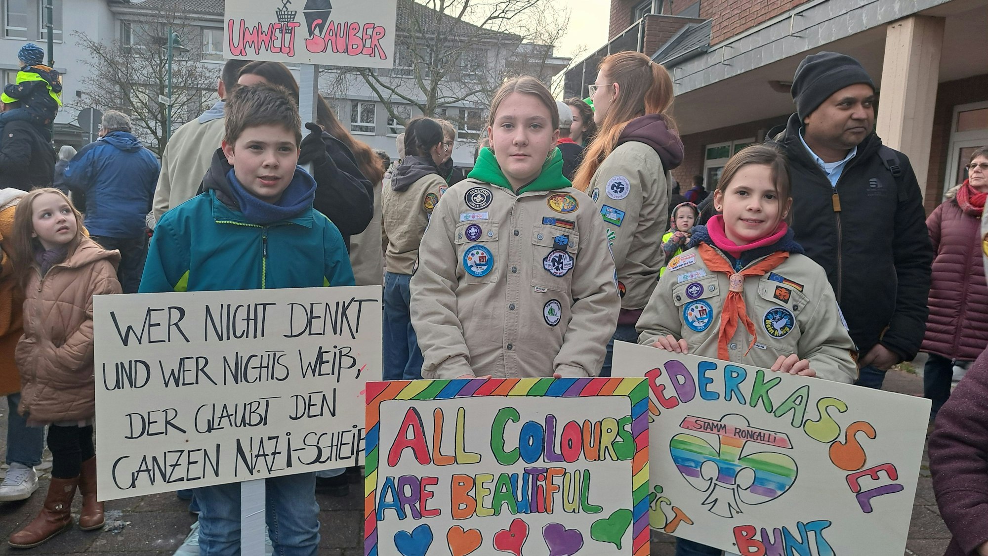 Pfadfinderinnen und Pfadfinder stehen bei der Niederkasseler Demonstration für Demokratie mit Plakaten auf dem Rathausplatz.