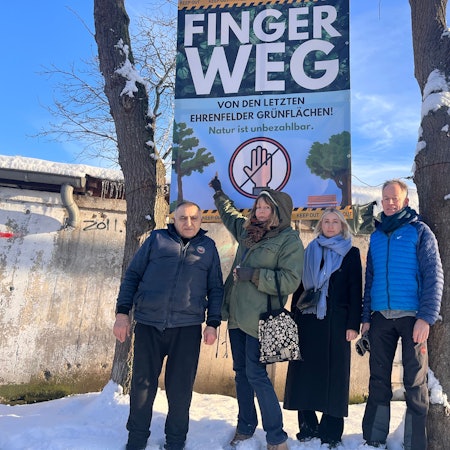 Zwei Männer und zwei Frauen stehen vor einem großen Protestplakat mit der Aufschrift Finger weg von den letzten Ehrenfelder Grünflächen.