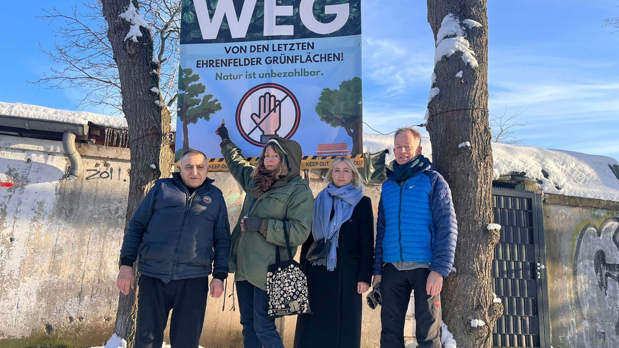 Zwei Männer und zwei Frauen stehen vor einem großen Protestplakat mit der Aufschrift Finger weg von den letzten Ehrenfelder Grünflächen.