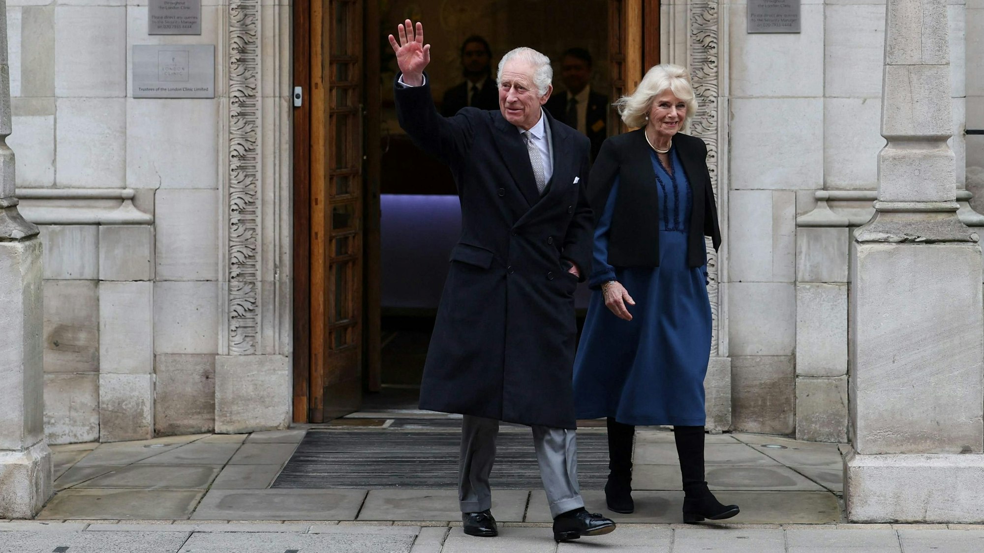König Charles winkt neben seiner Frau Königin Camilla beim Verlassen der Klinik.