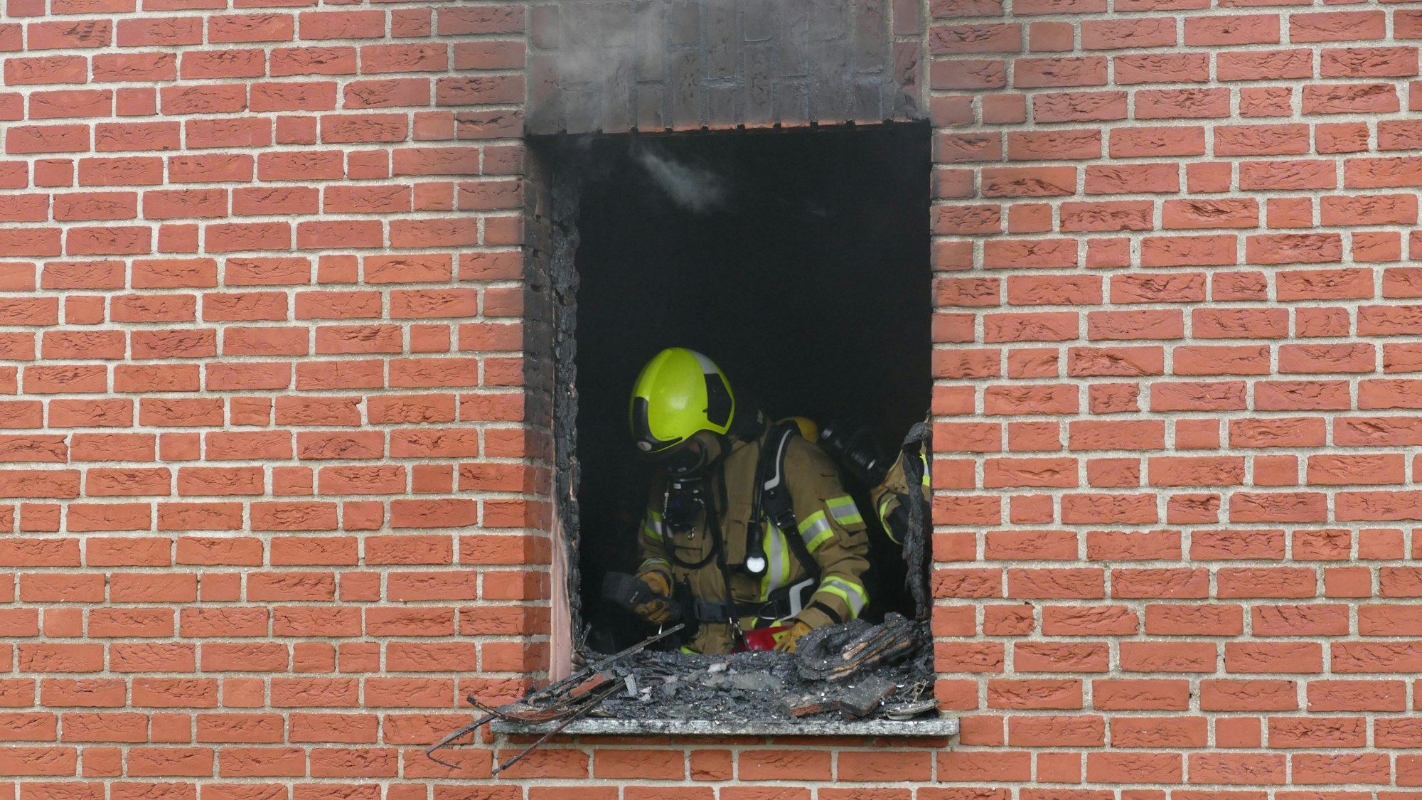 Feuerwehrleute stehen in dem ausgebrannten Raum.