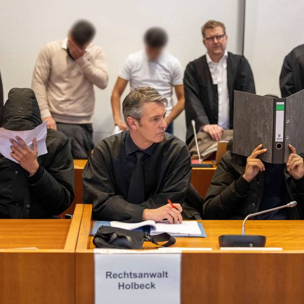 Vier der sieben Angeklagten und ihre Rechtsanwälte warten im Gerichtssaal auf den Beginn des Prozesses gegen sieben Angeklagte wegen Landfriedensbruch.