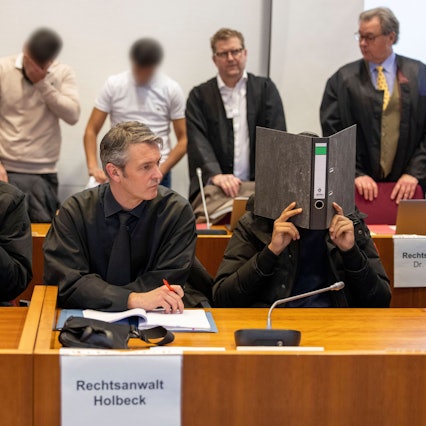 Vier der sieben Angeklagten und ihre Rechtsanwälte warten im Gerichtssaal auf den Beginn des Prozesses gegen sieben Angeklagte wegen Landfriedensbruch.