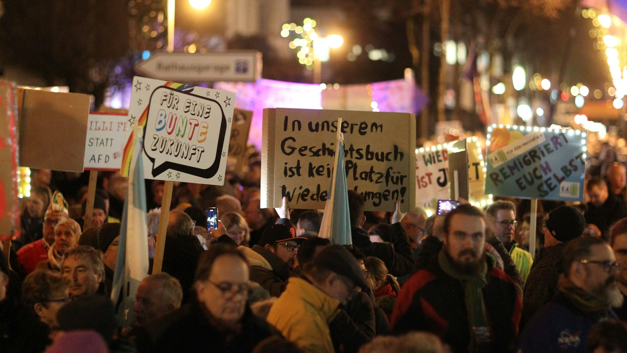 Menschen halten bei einer Demonstration Schilder in die Luft.