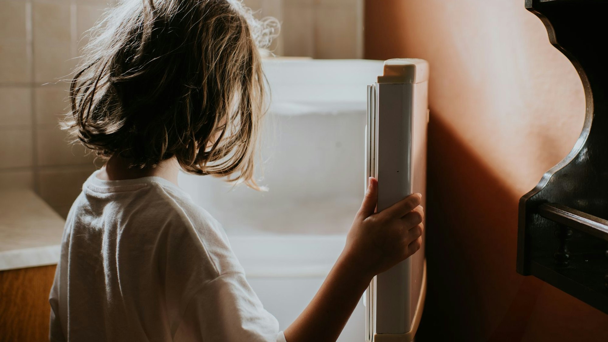 Ein Kind öffnet einen Kühlschrank, in dem sich nichts befindet.