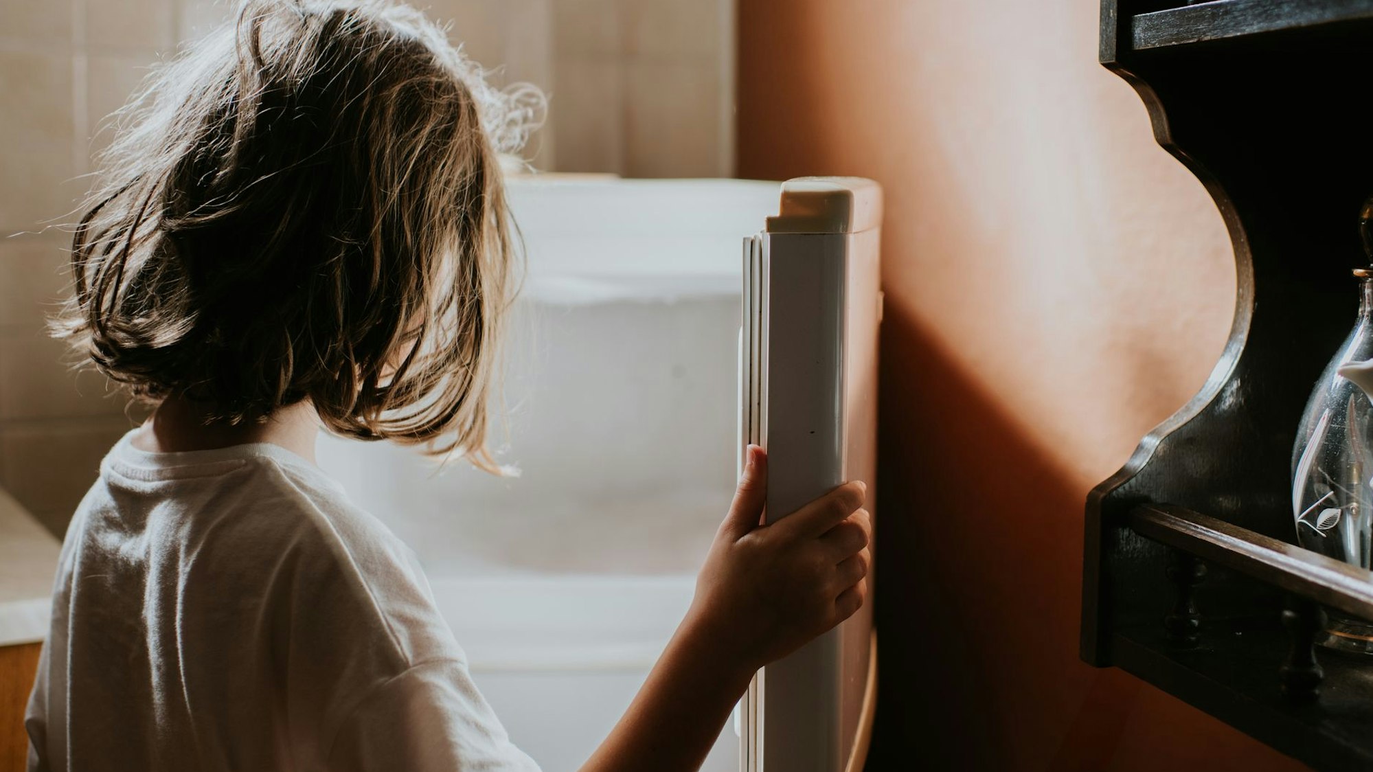 Ein kleines Mädchen steht vor einem leeren Kühlschrank.