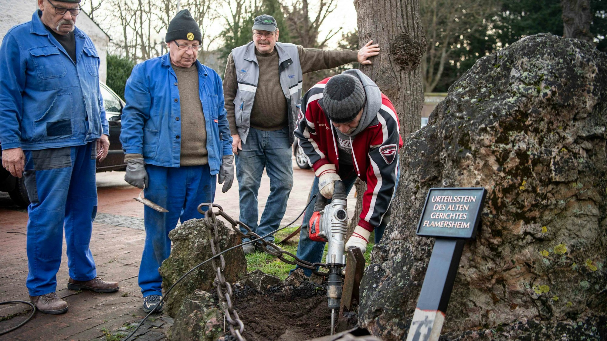 Das Bild zeigt einen Flamersheimer bei der Arbeit. Drei weitere Senioren schauen im dabei zu.
