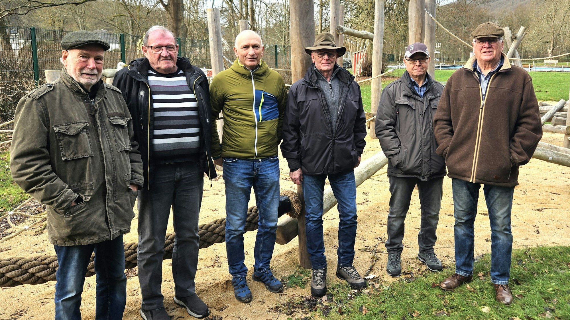 Sechs Männer, die „Rentner von Gemünd“, stehen auf einem Spielplatz.