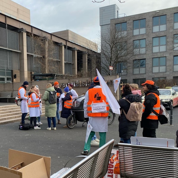 Am Eingang zur Uniklinik Köln stehen mehrere streikende Angestellte.