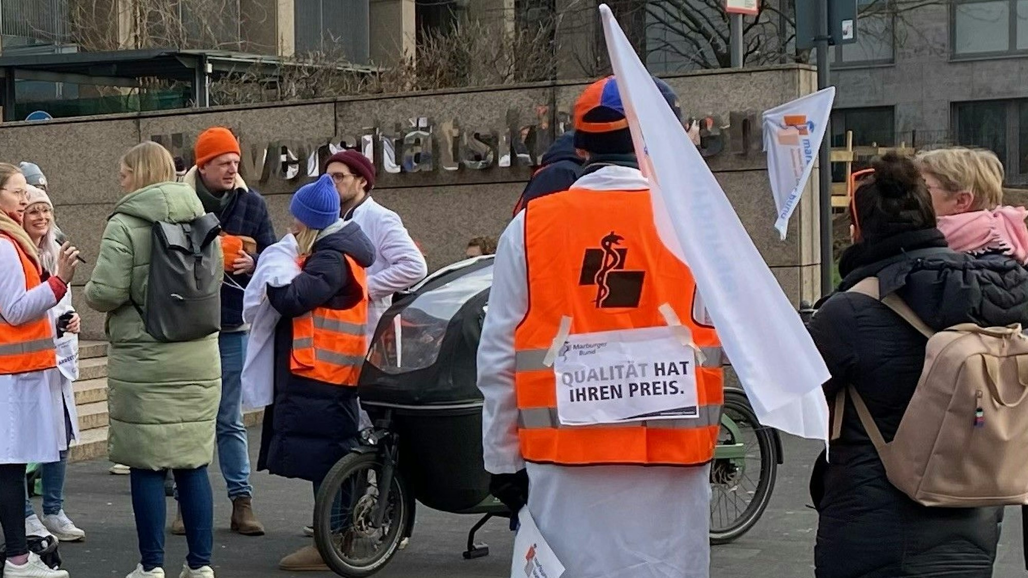 Am Eingang zur Uniklinik Köln stehen mehrere streikende Angestellte.