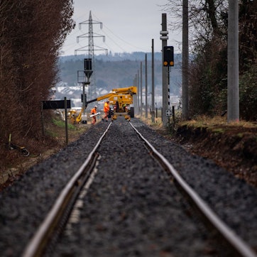 Arbeiter der Bahn bei der Sanierung der Bahnstrecke zwischen Euskirchen und Bad Münstereifel. Im Hintergrund ist der Mast einer Hochspannungsleitung zu sehen.