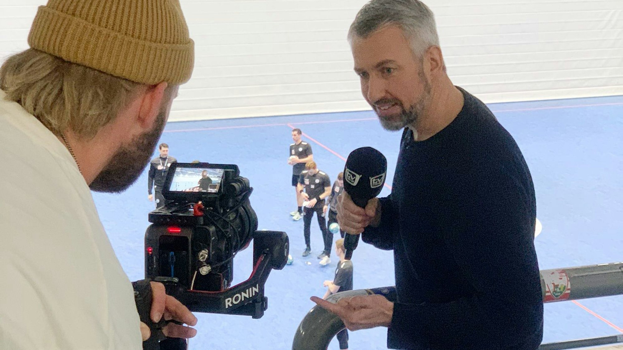 „TV Total“-Moderator Sebastian Pufpaff beim Handballtraining in der Schwalbe-Arena. Er spricht in ein Mikrofon und wird dabei von einem Kameramann gefilmt.