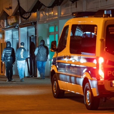 Ein Polizeiwagen fährt durch das Görlinger-Zentrum in der Nacht. Im Scheinwerferlicht stehen Jugendliche.